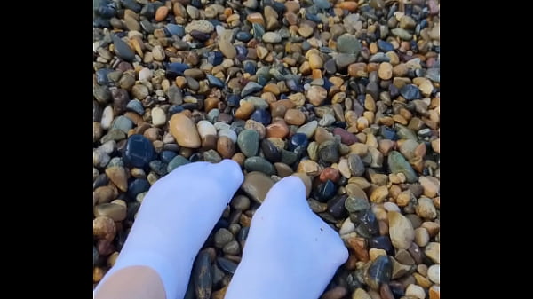 Playing with my feet in white socks with pebbles on the beach