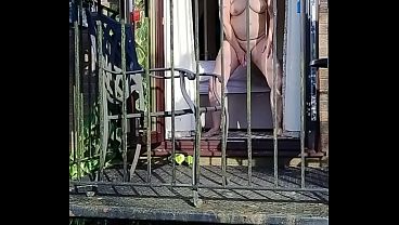 Naughty girl wanking in full view on the balcony